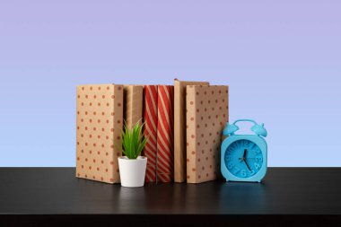 Siyah ahşap masada yığınla kitap.