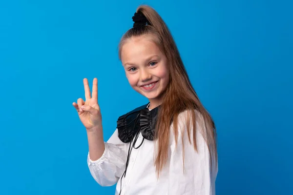 Giovane ragazza adolescente che mostra un simbolo di pace con le dita sullo sfondo blu — Foto Stock