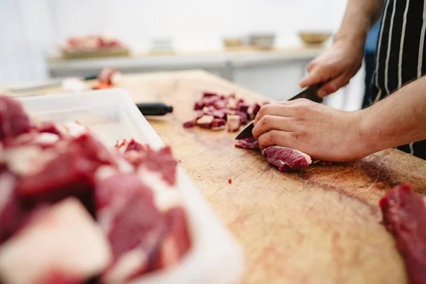 Carnicero cortando rebanadas de carne cruda en tablero de madera — Foto de Stock