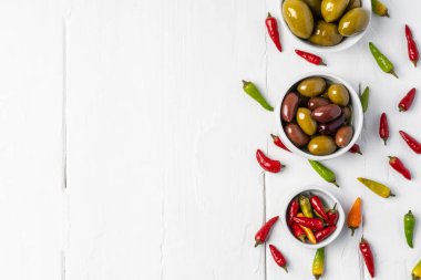 Beyaz ahşap arka planda acı biber ve marine edilmiş zeytin.