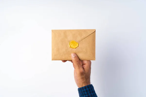 Männliche Hand hält geschlossenen Umschlag über der weißen Oberfläche — Stockfoto