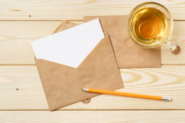 Envelopes with cup of tea on wooden table top — Stock Photo, Image