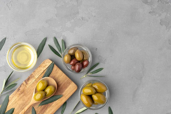 Плоска композиція з оливок та оливкової олії на сірому фоні — стокове фото