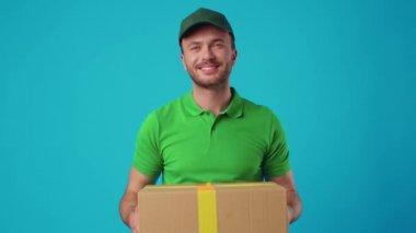 Yeşil üniformalı genç bir kurye elinde bir paket tutuyor.