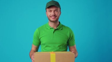 Yeşil üniformalı genç bir kurye elinde bir paket tutuyor.
