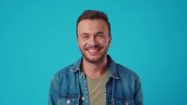 Mavi stüdyo geçmişine gülümseyen beyaz bir genç.