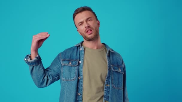 Mladý muž ukazující bla-bla gesto na pozadí modrého studia — Stock video