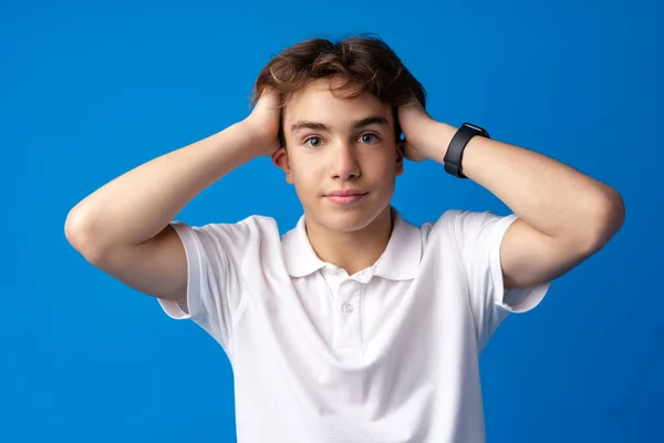 Sad teenager boy failed, touching face against blue background — Stock Photo, Image