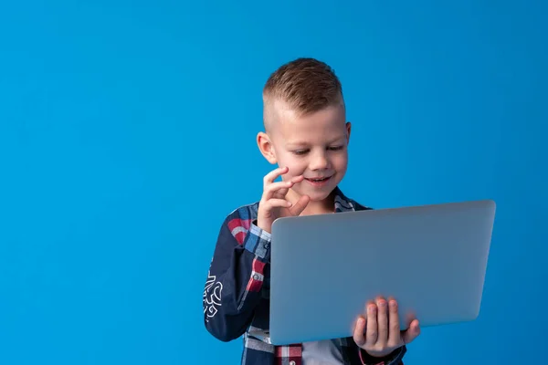 Niño inteligente con portátil aislado sobre fondo azul —  Fotos de Stock