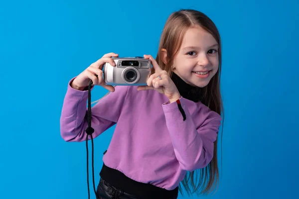 Retrato de uma menina com câmera contra fundo azul — Fotografia de Stock