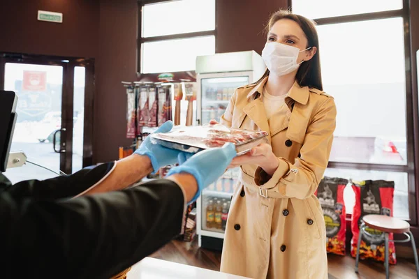 Egy fiatal nő orvosi maszkban nyers húst vásárol a boltban. — Stock Fotó