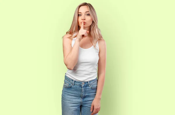Portret van jonge vrouw vragen om stil te zijn met de vinger op de lippen geïsoleerd op kleur achtergrond — Stockfoto