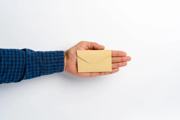 Mão masculina segurando envelope fechado acima da superfície branca — Fotografia de Stock