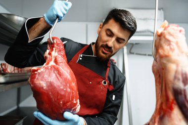 Erkek kasap et dükkanında asılı duruyor.