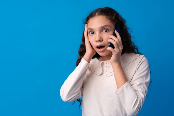 Jolie adolescente parlant sur le téléphone mobile sur fond bleu — Photo