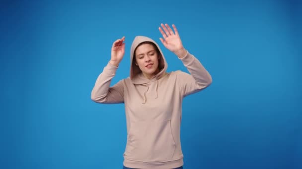 Lykkelig ung kvinde danser på blå baggrund – Stock-video
