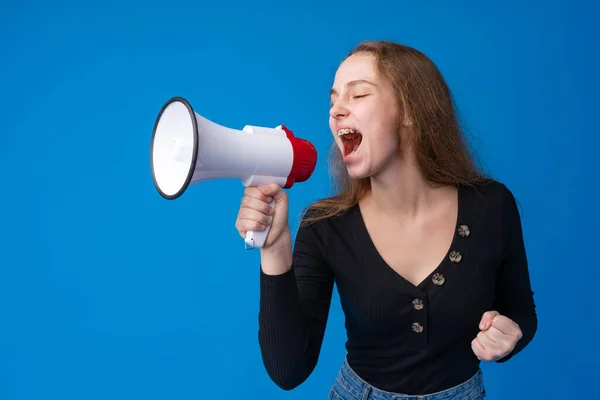 Adolescente fazendo anúncio com megafone no estúdio azul — Fotografia de Stock