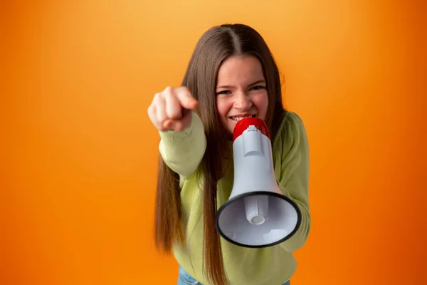 Teenager-Mädchen macht Ansage mit Megafon vor orangefarbenem Hintergrund — Stockfoto