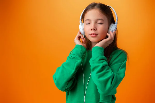 Retrato de chica adolescente feliz moderna con auriculares sobre fondo naranja — Foto de Stock