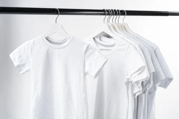 Kleider hängen auf Kleiderständern über weißem Hintergrund. — Stockfoto