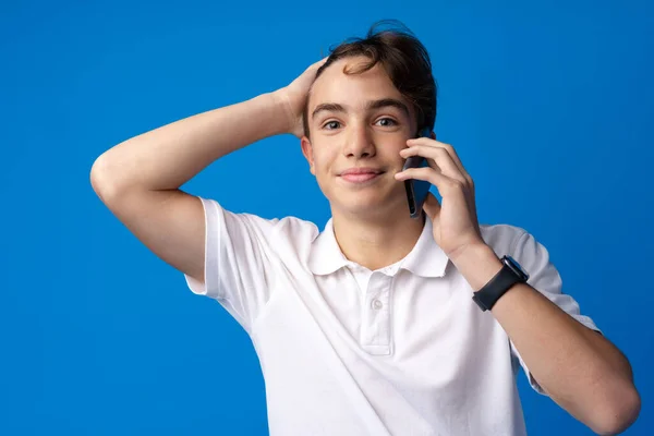 Boy talking by mobile phone on blue background — Stock Photo, Image
