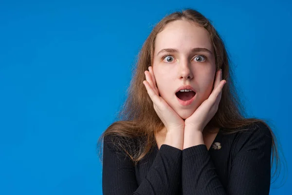 Chocado e surpreso jovem adolescente menina contra fundo azul — Fotografia de Stock