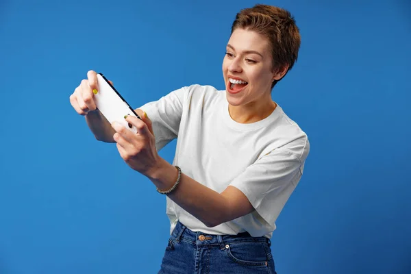 Boldog vonzó fiatal nő élvezni videojáték okostelefon, stúdió fotó — Stock Fotó