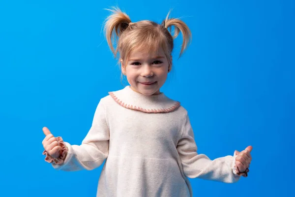 Aranyos kislány mutatja hüvelykujját fel a kék háttér — Stock Fotó