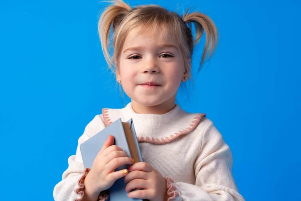 Cute little girl z książki na niebieskim tle — Zdjęcie stockowe