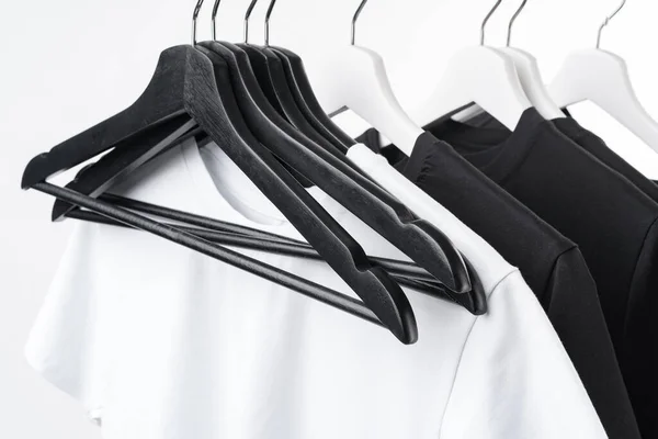 Schwarz-weiße T-Shirts auf Kleiderbügeln auf Metallgestell isoliert auf weiß — Stockfoto