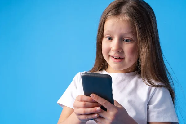 Menina usando telefone móvel.Contra fundo azul — Fotografia de Stock