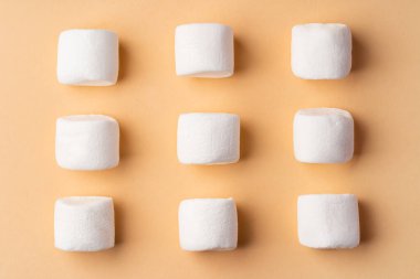 Bej stüdyo arka planında pofuduk marşmelovlar, üst manzara.