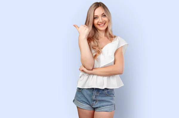 Junge lächelnde Frau zeigt auf Kopierraum auf farbigem Hintergrund — Stockfoto