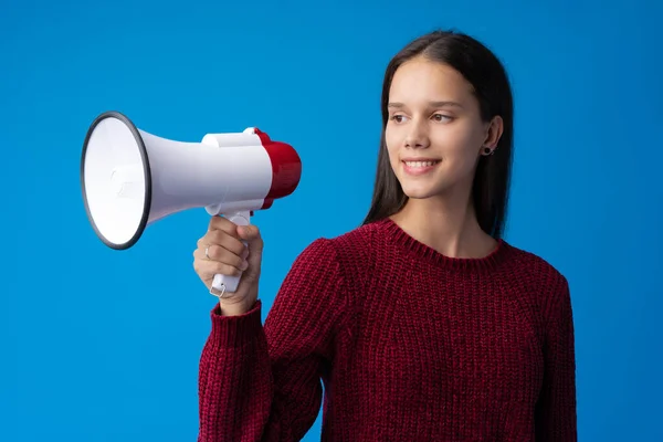 Adolescente fazendo anúncio com megafone no estúdio azul — Fotografia de Stock