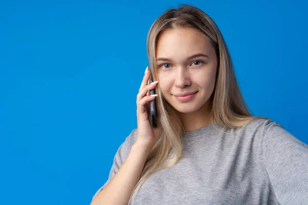 Csinos tizenéves lány beszél a mobiltelefon kék háttér — Stock Fotó