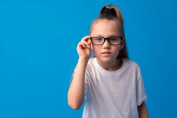 Tini lány beállítása szemüvegét kék háttér — Stock Fotó