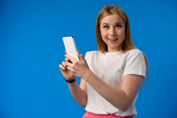 Emocionada joven sorprendida usando teléfono móvil contra fondo de estudio — Foto de Stock