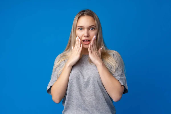 Chocado e surpreso jovem adolescente menina contra fundo azul — Fotografia de Stock