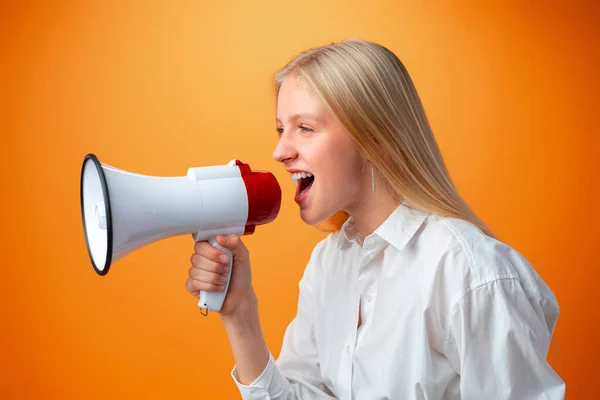 Adolescente fazendo anúncio com megafone contra fundo laranja — Fotografia de Stock