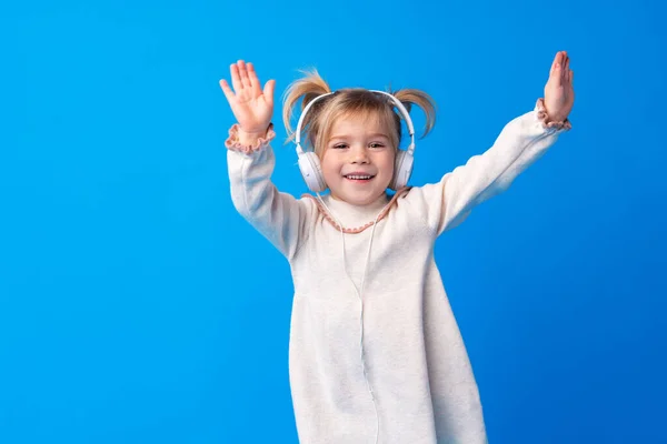 Kislány gyermek visel fejhallgató zenét hallgatni a kék háttér — Stock Fotó