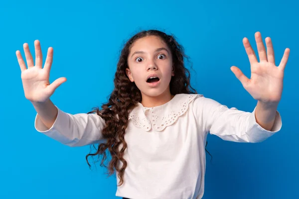 Jeune fille aux cheveux bouclés foncés montrant écran de smartphone sur fond bleu — Photo