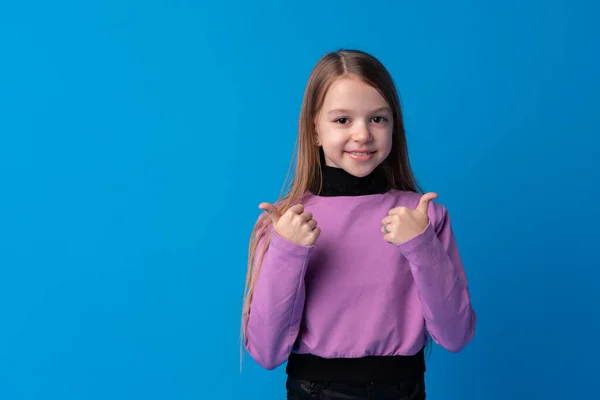 Portré tini lány, hogy hüvelykujj fel gesztus a kék háttér — Stock Fotó