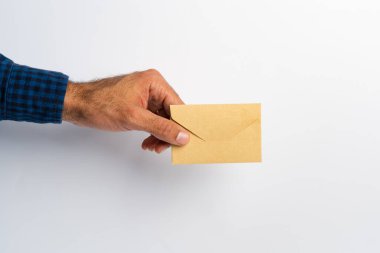 Erkek el beyaz yüzey üzerinde kapalı bir zarf tutuyor