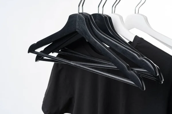 Black T-shirt on hangers on metal rack isolated on white background — Stock Photo, Image