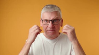 Sarı arka planda patlayan kafa hareketleriyle kıdemli adam.