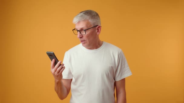 Беспокойный пожилой человек, старый работник смотрит на мобильный телефон — стоковое видео
