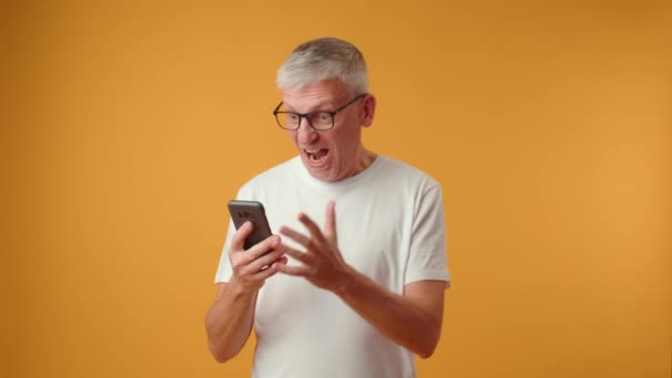 Anciano jubilado mirando la pantalla del teléfono, celebrando recibir un mensaje con buenas noticias — Vídeos de Stock