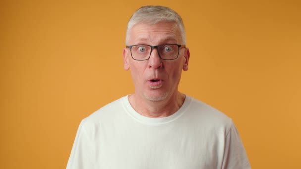 Красивий старший чоловік в окулярах боїться і шокований з несподіваним виразом — стокове відео