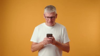 Yaşlı emekli adam telefon ekranına bakıyor. Mesajı iyi haberlerle kutluyor.