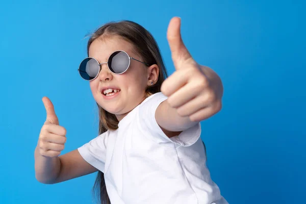 Retrato de menina adolescente fazendo gesto de polegar no fundo azul — Fotografia de Stock